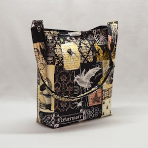 Pode incluir: Uma sacola preta com tema de Halloween. A sacola apresenta um design de patchwork com imagens de morcegos, aranhas, caveiras e a palavra "Nevermore". A sacola tem uma al&ccedil;a de ombro e formato retangular.