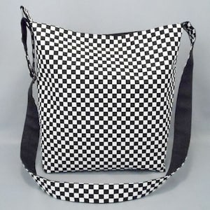 May include: Black and white checkered fabric tote bag with a black adjustable shoulder strap.