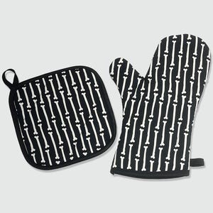 May include: Black and white oven mitt and pot holder set. The kitchen textiles feature a repeating pattern of white bones on a black background. The pot holder is square with a black loop for hanging. The oven mitt has a black trim.