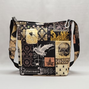 Pode incluir: Bolsa transversal preta e bege com um design de patchwork com caveiras, morcegos, aranhas e padr&otilde;es ornamentados. A bolsa tem uma al&ccedil;a preta ajust&aacute;vel e um fecho prateado. O texto "Nevermore" &eacute; vis&iacute;vel.