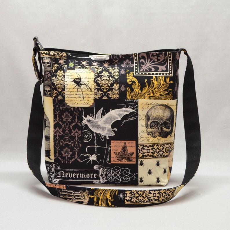 Pode incluir: Bolsa transversal preta com um design de patchwork com caveiras, morcegos, aranhas e padr&otilde;es ornamentados. A bolsa tem uma al&ccedil;a preta ajust&aacute;vel e a palavra "Nevermore" est&aacute; impressa na frente.
