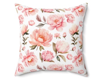 Op de afbeelding: Een wit kussen met een roze bloemenpatroon. Het kussen heeft een herhalend patroon van roze pioenen met groene bladeren.