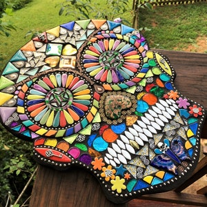 May include: A colorful mosaic skull, featuring a variety of shapes and colors. The mosaic includes triangles, squares, and other geometric forms in shades of blue, orange, yellow, and green. The skull is a decorative piece, likely for home decor.