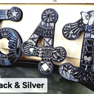 three black and silver mosaic letters on a wall, with the text "Black & Silver" below them.