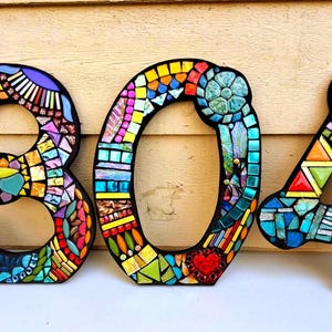 a creative and colorful display of mosaic tiles, forming the numbers "301" on a wall.