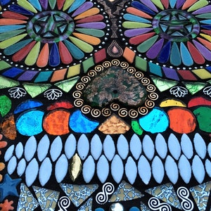 May include: A colorful mosaic skull design with a black background. The mosaic features various shapes and colors, including blue, orange, green, and purple. The design includes star and spiral patterns.