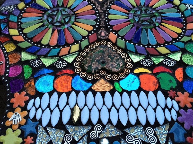 May include: A colorful mosaic skull design with a black background. The mosaic features various shapes and colors, including blue, orange, green, and purple. The design includes star and spiral patterns.