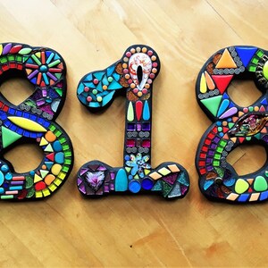 three colorful mosaic letters on a wooden surface.