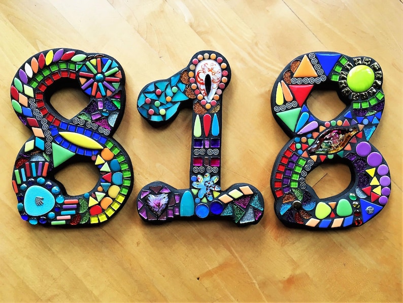 three colorful mosaic letters on a wooden surface.