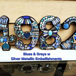 a large number 4982 made of various metallic embellishments, including blue and silver pieces, arranged in a visually striking and creative manner.
