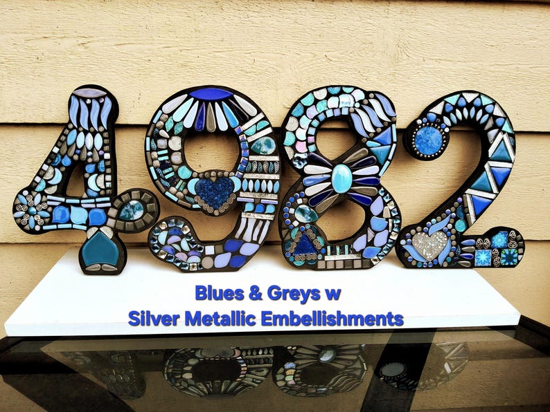 a large number 4982 made of various metallic embellishments, including blue and silver pieces, arranged in a visually striking and creative manner.