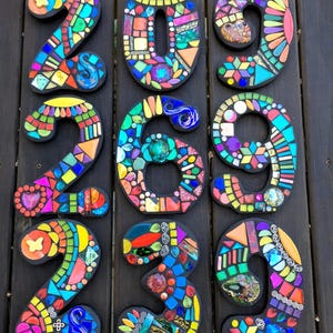 nine colorful mosaic pieces arranged in a grid pattern on a wooden surface.