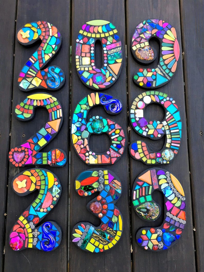 nine colorful mosaic pieces arranged in a grid pattern on a wooden surface.