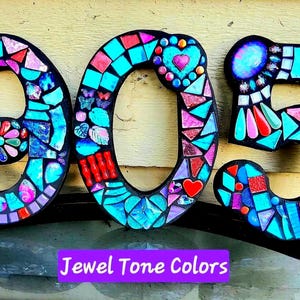 The image is a mosaic-style number 9, 5, and 0, made up of colorful tiles in various shades and patterns.