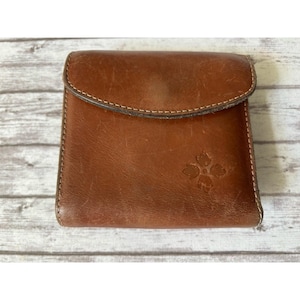 May include: A brown leather wallet with a flap closure. The wallet features a floral design on the front and white stitching around the edges. The leather has a worn appearance.