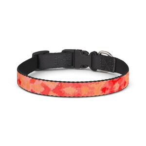 Op de afbeelding: Een halsband voor huisdieren met een levendig rood en oranje tie-dye patroon op de buitenste band. De halsband is voorzien van een zwarte kunststof klikgesp, een zwarte verstelbare schuif en een zilverkleurige metalen D-ring voor een riem.
