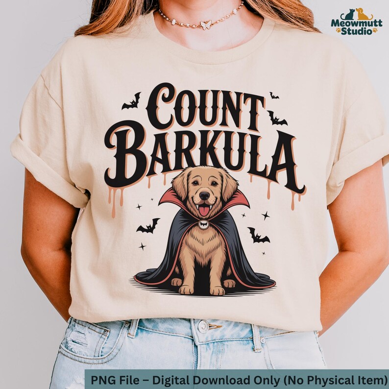 May include: Beige t-shirt featuring a cartoon illustration of a golden retriever dressed as a vampire, with the text "COUNT BARKULA". The design includes bats and dripping blood accents, perfect for Halloween.
