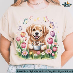 Op de afbeelding: Beige T-shirt met een afbeelding van een lachende golden retriever die een koffiekopje vasthoudt. Het ontwerp bevat vlinders, tulpen en madeliefjes. De tekst "Meowmutt Studio" staat rechtsboven en "PNG File - Digital Download Only (No Physical Item)" onderaan.