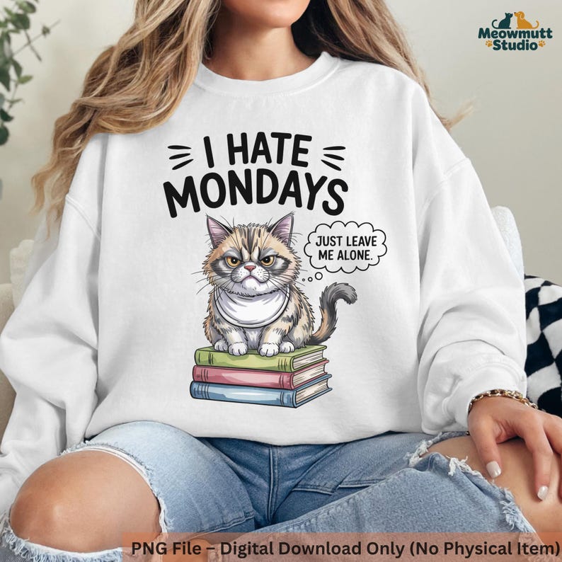 May include: White sweatshirt with the text "I HATE MONDAYS" and a grumpy cat illustration. The cat sits on a stack of books and has a speech bubble that says "JUST LEAVE ME ALONE."