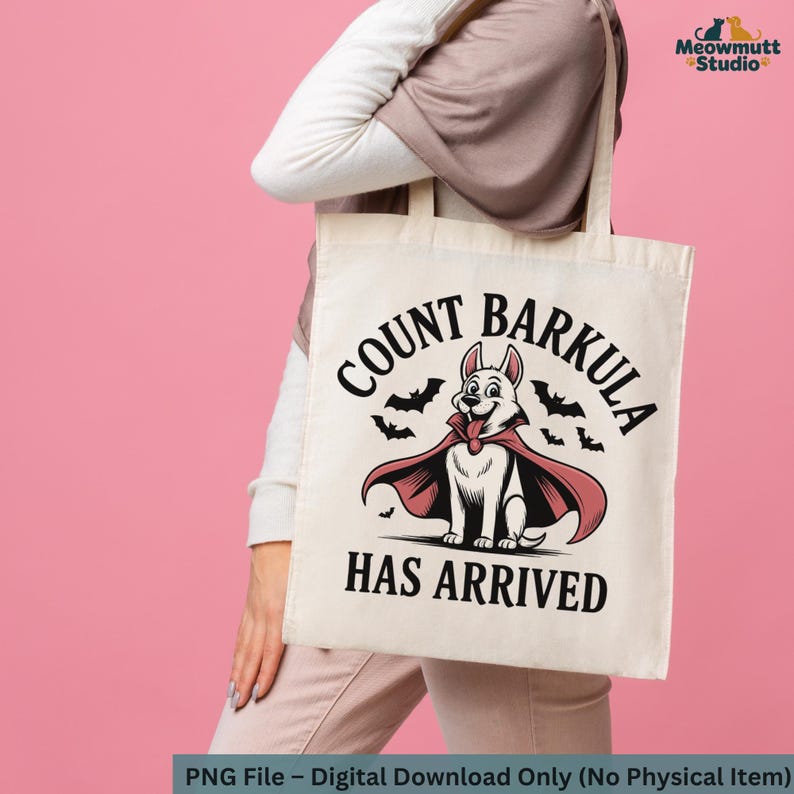 May include: A cream-colored tote bag featuring a cartoon dog dressed as a vampire with the text "COUNT BARKULA HAS ARRIVED". The dog is white with a red cape and is surrounded by bats. The bag is held by a person.