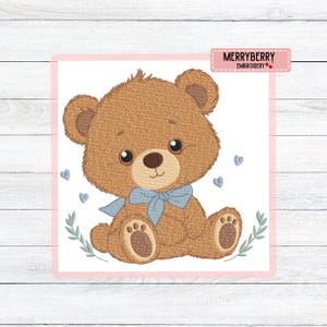 Può includere: Un orsacchiotto marrone con un papillon blu, ricamato su sfondo bianco. L'orso ha grandi occhi scuri ed è circondato da piccoli cuori blu e foglie verdi. L'immagine ha un bordo rosa e il testo "MERRYBERRY EMBROIDERY".