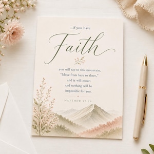 May include: A cream-colored greeting card with the word "Faith" in elegant script. The card features a watercolor mountain scene and a quote from Matthew 17:20. A gold-tipped pen rests beside the card, with floral accents.