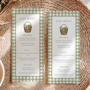 May include: Two rectangular menu cards featuring a sage green and white gingham border. Each card displays the text THE MENU, a watercolor illustration of a vegetable basket, and sections for starters, main, and dessert with listed food items.