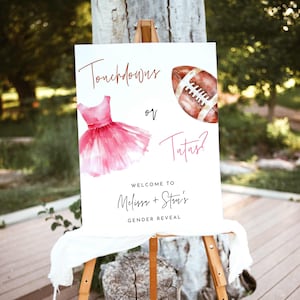 May include: A white rectangular gender reveal sign featuring a watercolor pink tutu and a brown football. The text reads Touchdowns or Tutus? Welcome to Melissa + Stu's Gender Reveal. The sign is displayed on a wooden easel stand.