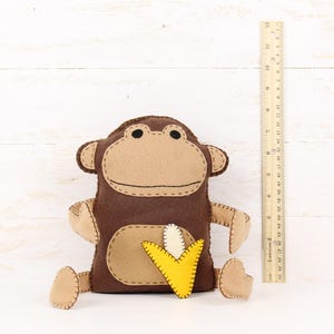 Felt monkey stuffed animal next to a ruler