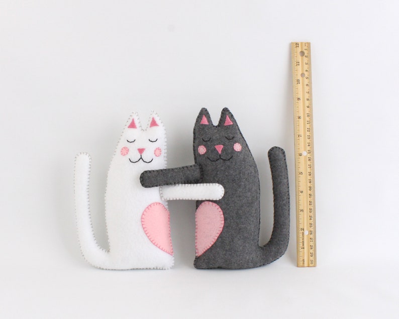 Felt stuffed cats next to a ruler to show relative size