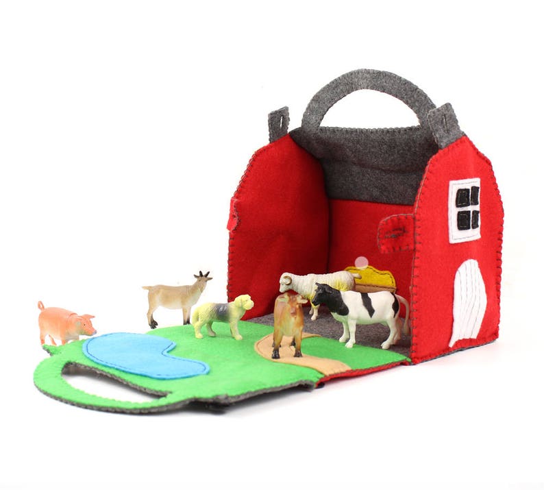 Hand sewn toy barn opened up with plastic farm animal toys inside