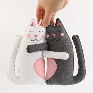 Hand holding plush felt hand sewn cats