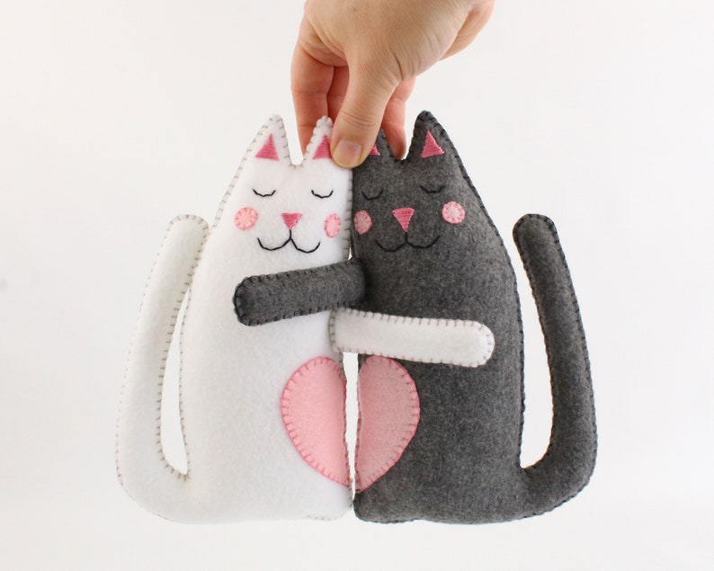 Hand holding plush felt hand sewn cats