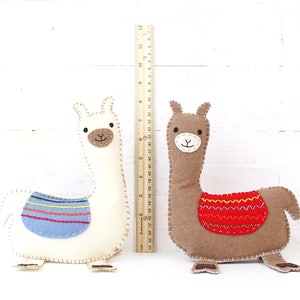 Felt hand sewn llamas next to a ruler