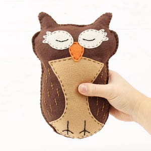 Hand holding a hand stitched felt sleepy owl