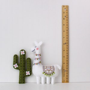 Felt hand sewn cactus and llama next to a ruler