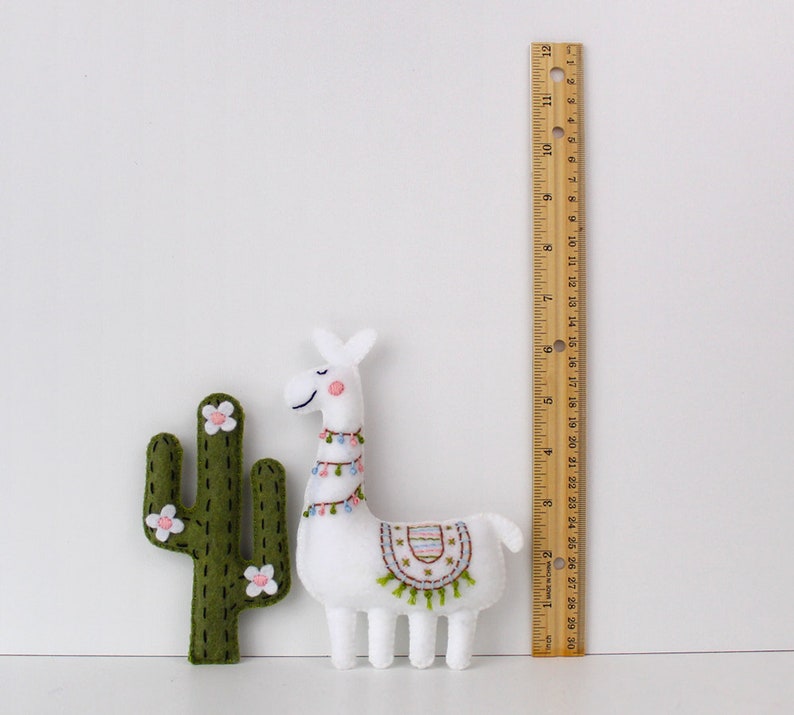 Felt hand sewn cactus and llama next to a ruler