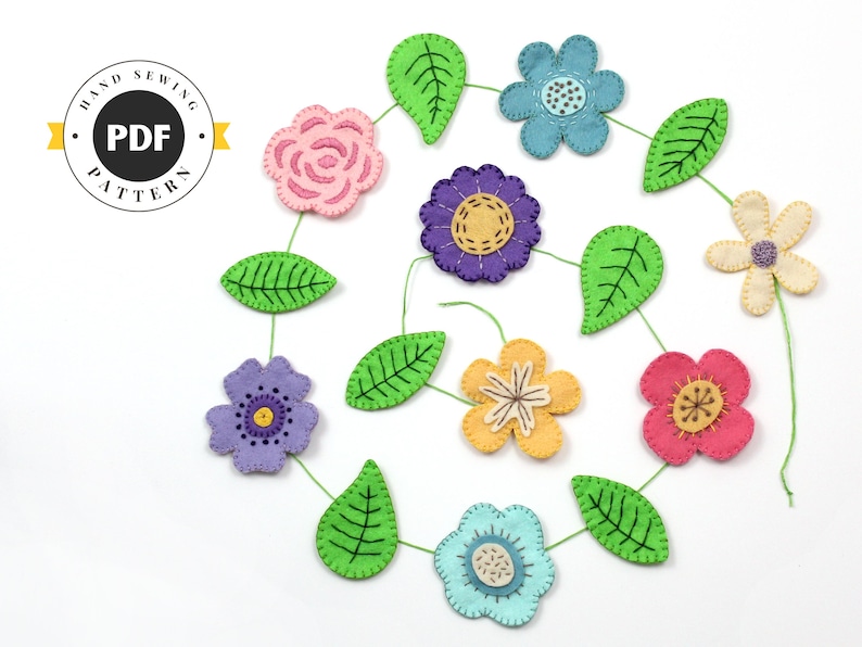 May include: A colorful felt flower garland with various flower designs in pink, blue, purple, and yellow, connected by green stems and leaves. The image includes a circular logo that says "HAND SEWING PDF PATTERN".