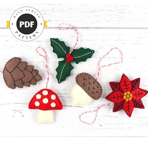 May include: Five felt Christmas ornaments with red and white twine hanging from them. The ornaments are a brown pine cone, a green holly sprig, a white acorn, a red and white mushroom, and a red poinsettia.