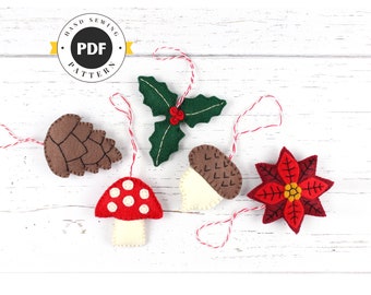 May include: Five felt Christmas ornaments with red and white twine hanging from them. The ornaments are a brown pine cone, a green holly sprig, a white acorn, a red and white mushroom, and a red poinsettia.