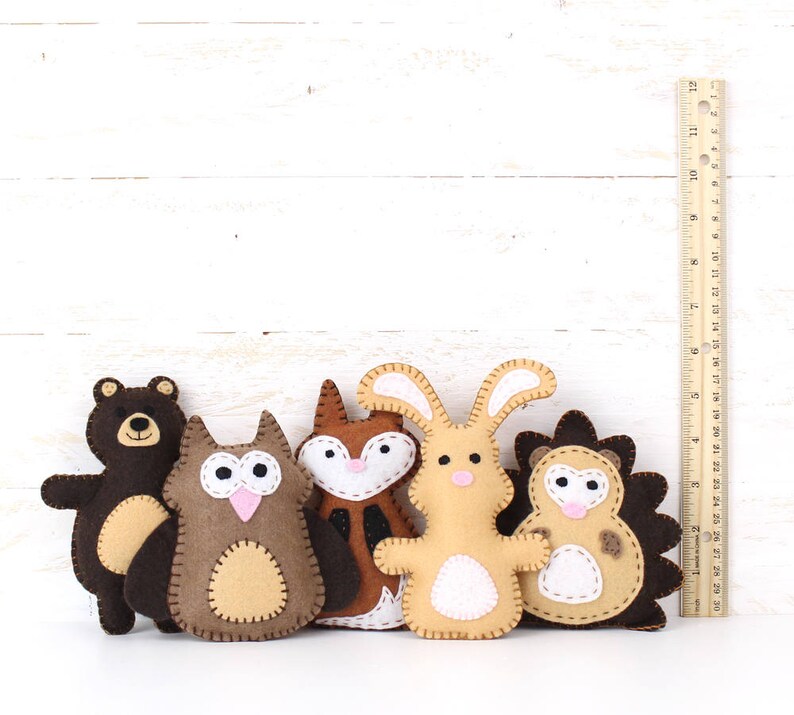 Felt plush bear, owl, fox, rabbit, and hedgehog next to a ruler