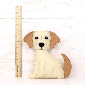 Felt plush golden lab puppy next to a ruler to show relative size