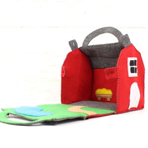 Red felt toy barn open to reveal pond and path