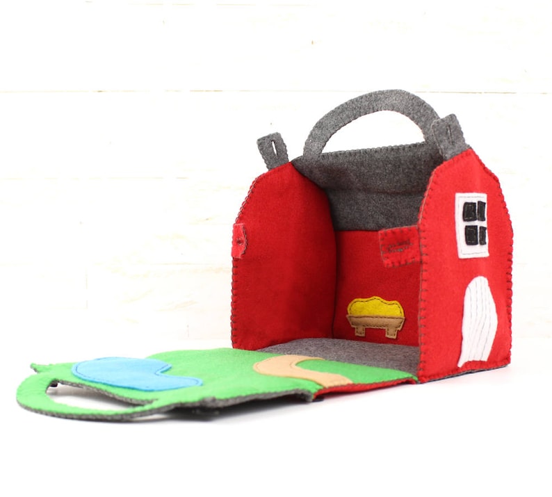 Red felt toy barn open to reveal pond and path