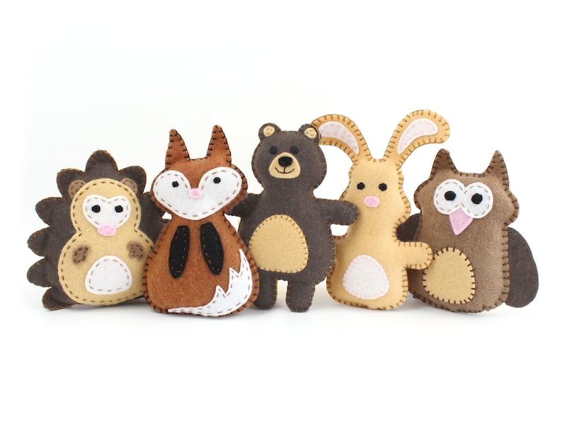 A set of five small woodland animals made from hand sewing patterns: a hedgehog, fox, bear, bunny, and owl