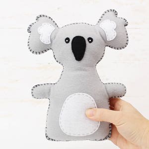 Light gray plush koala bear hand sewn with felt and embroidery floss, held in a hand