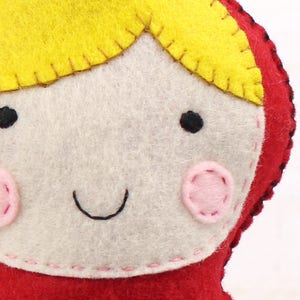 Close up of stitching on the face of hand sewn felt little red riding hood