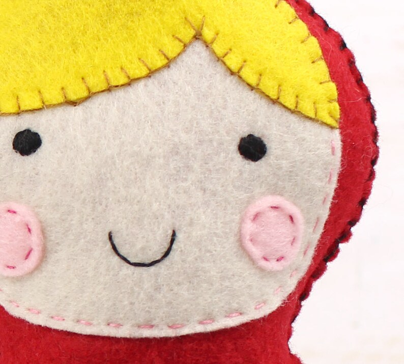 Close up of stitching on the face of hand sewn felt little red riding hood