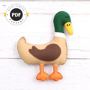 May include: A felt duck sewing pattern, with a green head, brown body, and orange feet. The pattern is labeled "Hand Sewing PDF Pattern".
