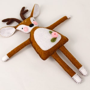 Plush red deer handmade from felt, with a pink flower, pink cheeks, and stitched embellishments